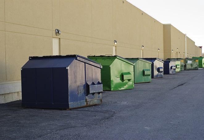 a construction worker unloading debris into a blue dumpster in Ammon, ID